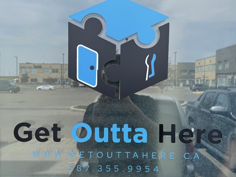 Logo for Get Outta Here escape rooms as seen on the building door.