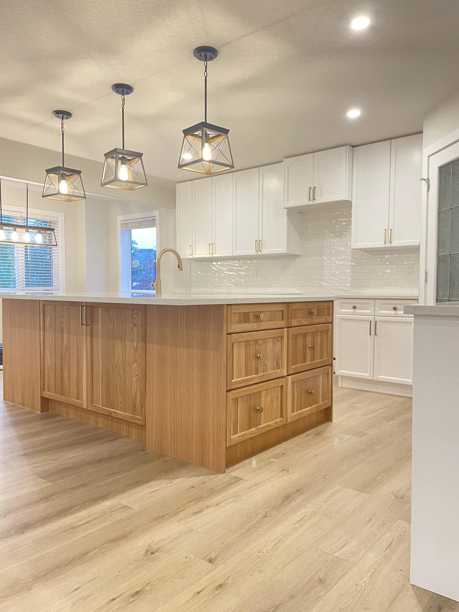A wide view of a modern kitchen with large island and accent overhead lighting.