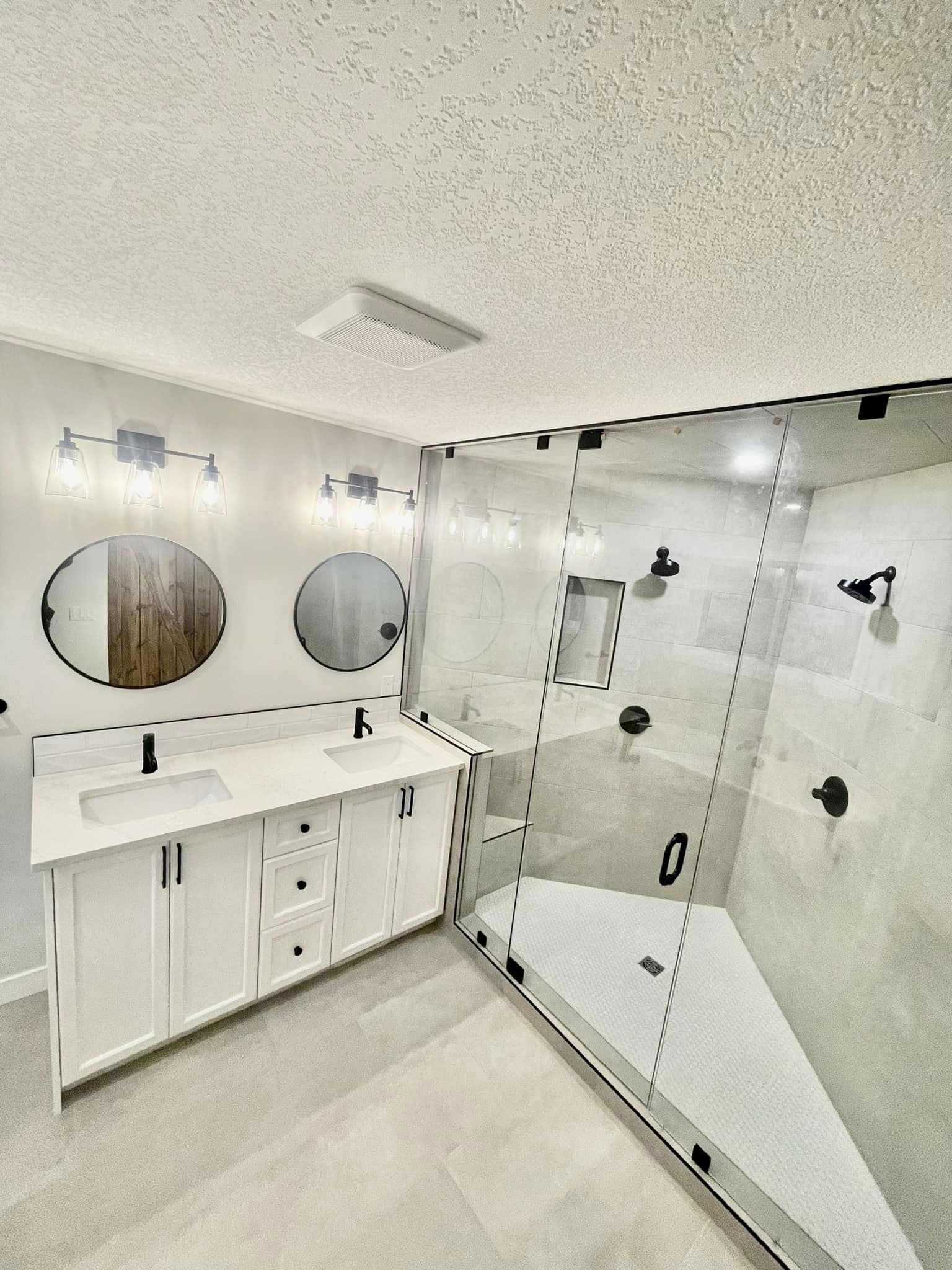 A modern bathroom with newly renovated shower and dual sink/mirror.