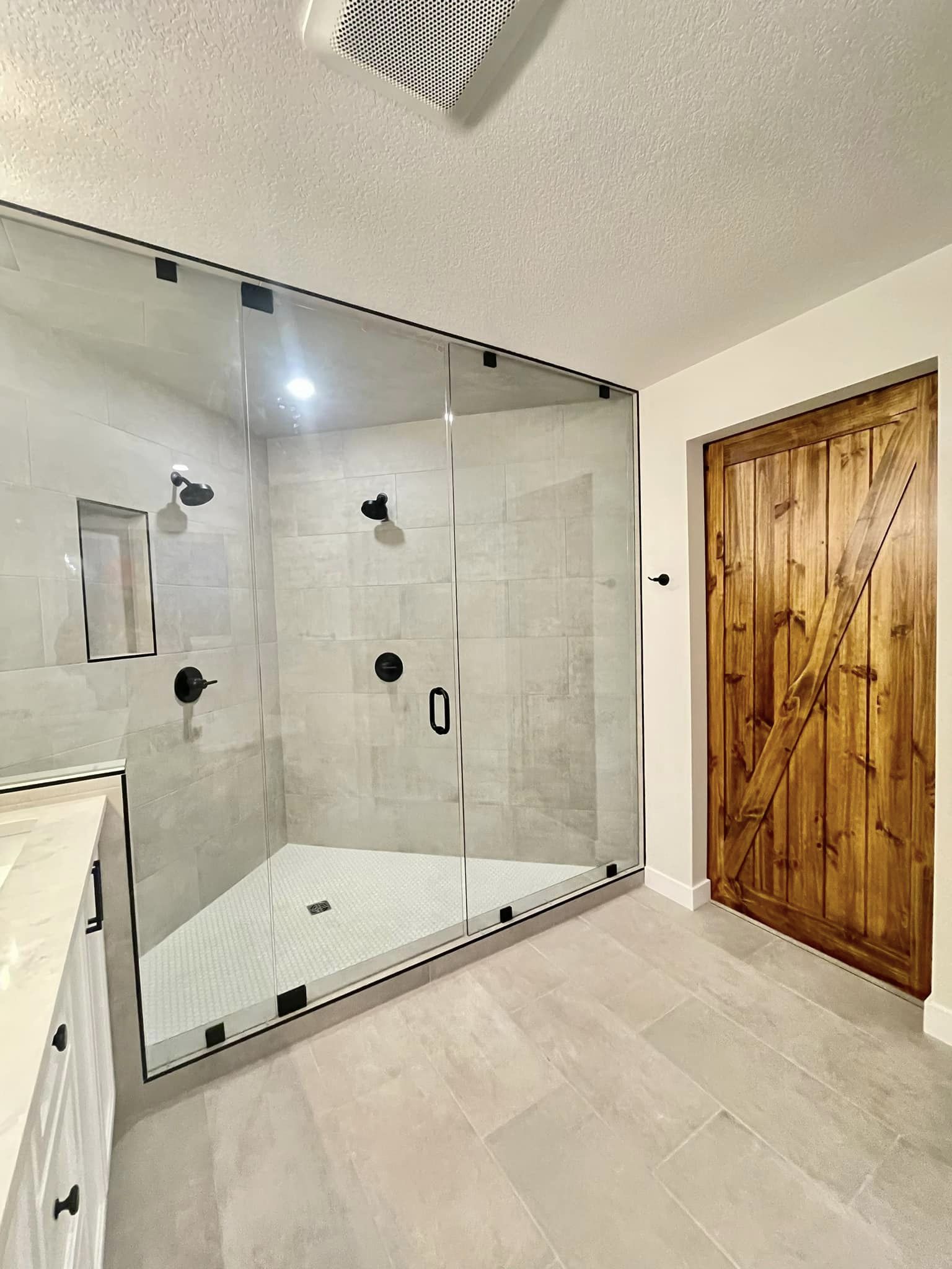 Modern bathroom with newly renovated dual shower and barn door entry.